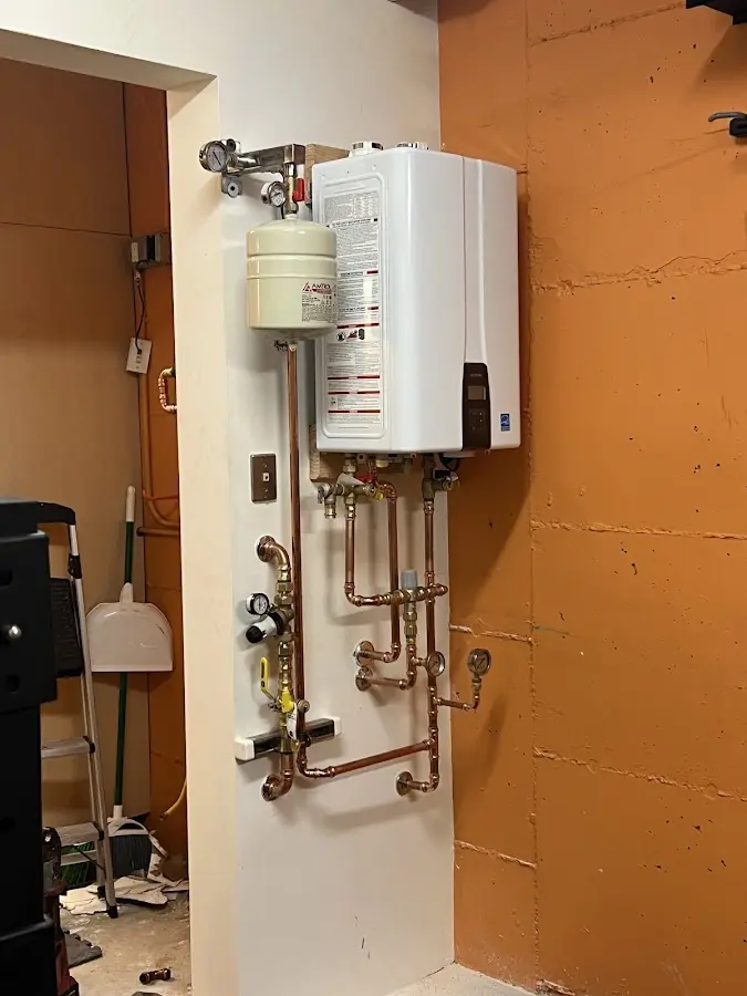 Plumbing technician inspecting water heater connections in Olive